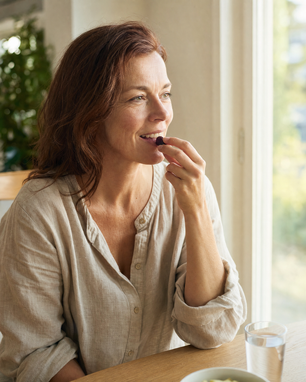 Woman taking a DailyBioLabs GLP-1 Body Shield gummy